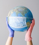 Hands with latext gloves holding a globe with a face mask. Photo by Anna Shvets from Pexels
